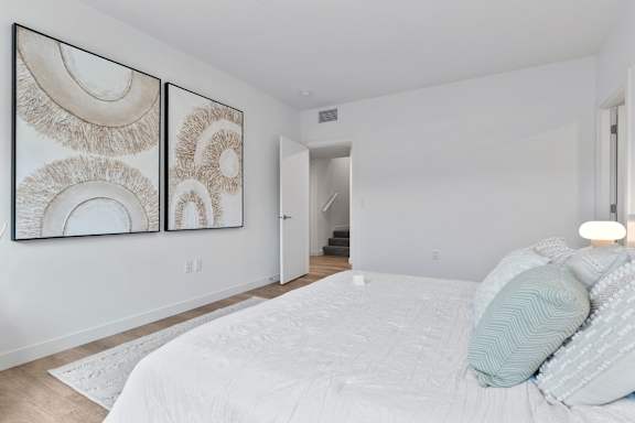 A bedroom with a large bed and two framed artworks on the wall.