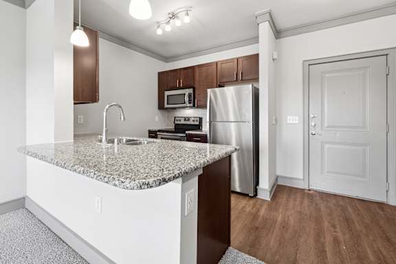 A kitchen with a granite countertop and stainless steel appliances.