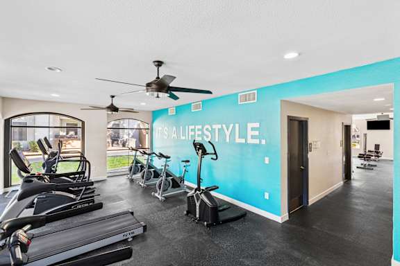 A gym with a row of treadmills and a wall that says