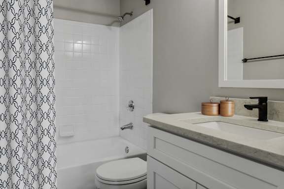 A bathroom with a toilet, sink, and shower curtain.