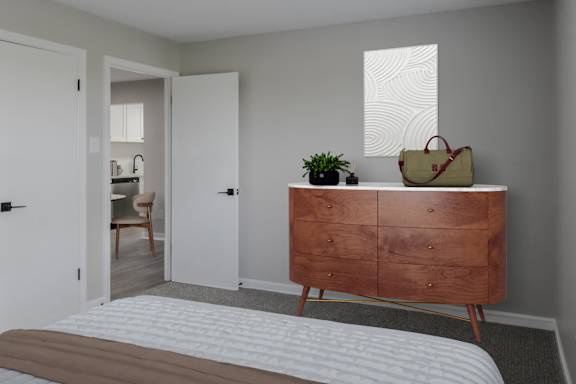 A brown wooden dresser with a plant on top and a beige bag on it.