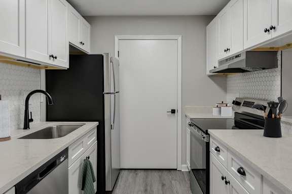A kitchen with black and white appliances and cabinets.