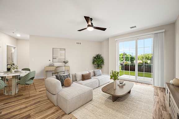 A living room with a sofa, a coffee table, a dining table, and a ceiling fan.