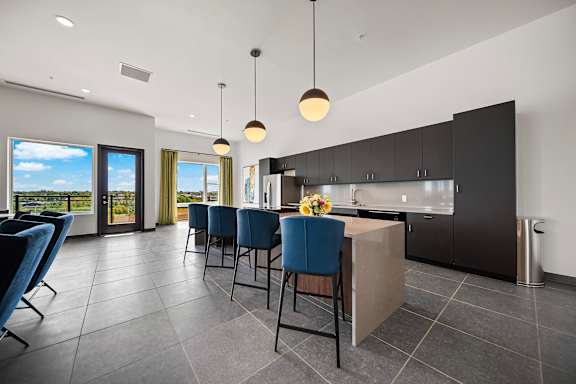 A modern kitchen with blue chairs and a dining table.