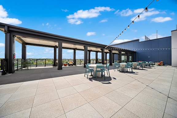 A patio with tables and chairs under a roof.