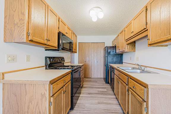 A kitchen with wooden cabinets and a black refrigerator.