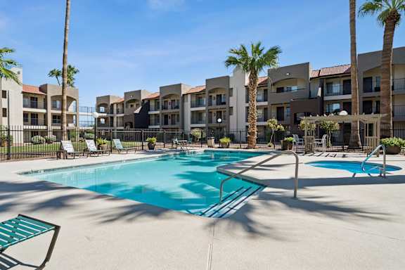 A swimming pool surrounded by palm trees and apartment buildings.