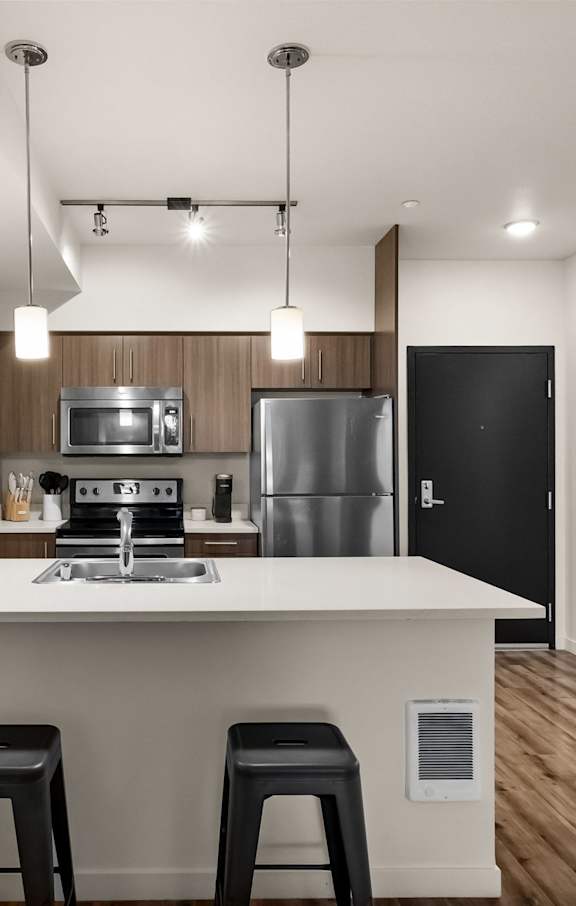 A modern kitchen with a white countertop and black stools.