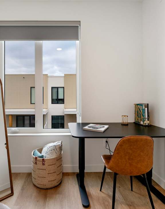 a desk and a mirror in a room with a window