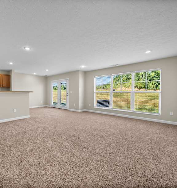 A spacious room with carpeted floor and large windows.
