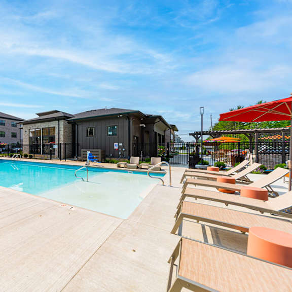 A pool surrounded by sun loungers and umbrellas.