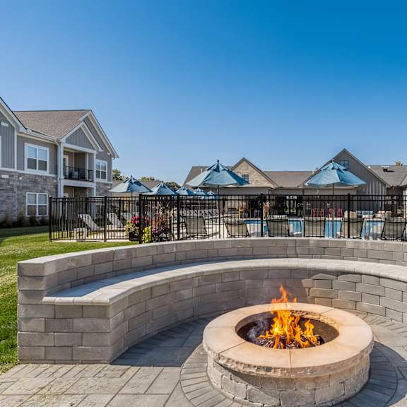 A fire pit sits in the middle of a brick patio.