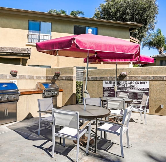a patio with tables and chairs and a barbecue grill