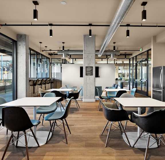 A modern dining area with white tables and black chairs.