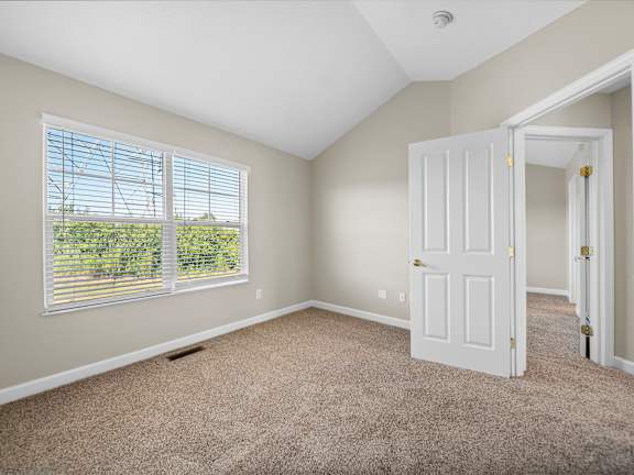 A room with a carpeted floor and a window with blinds.
