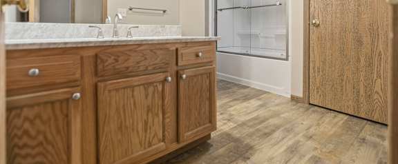 A bathroom with wooden cabinets and a marble countertop.