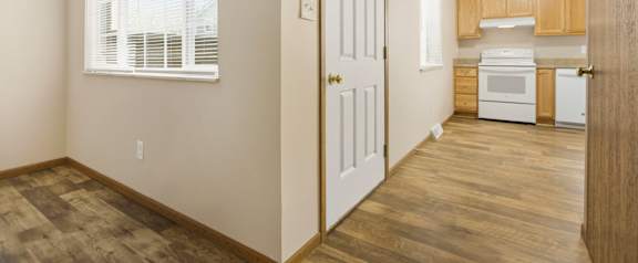 A kitchen area with a white door and a window with blinds.