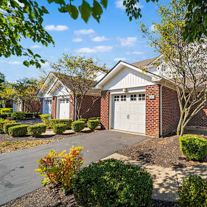 A house with a white garage door is surrounded by a well-manicured garden.