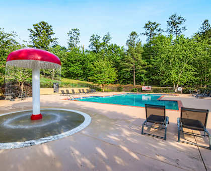 a fountain with a red umbrella next to a pool