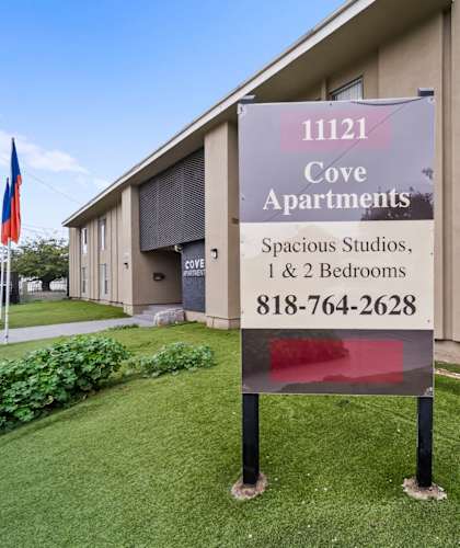 A sign for Cove Apartments is displayed in front of a building.