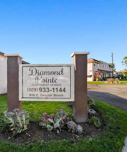 A sign for Diamond Apartments with a phone number and address.