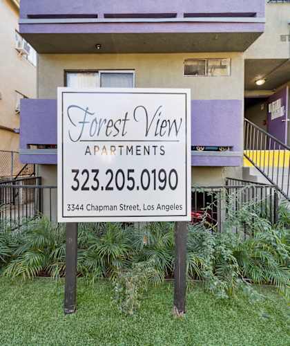A sign for Forest View Apartments is in front of a building.