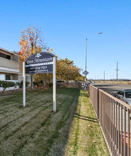 A sign for Iron Mountain Apartments stands in front of a building.