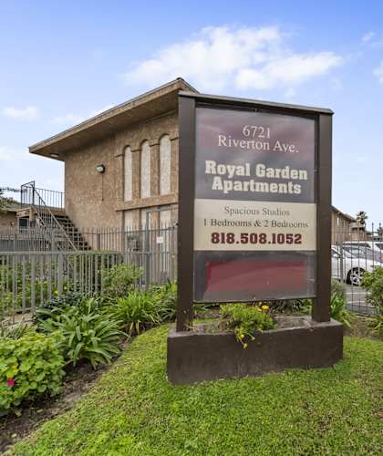 A sign for the Royal Garden Apartments stands in front of a building.