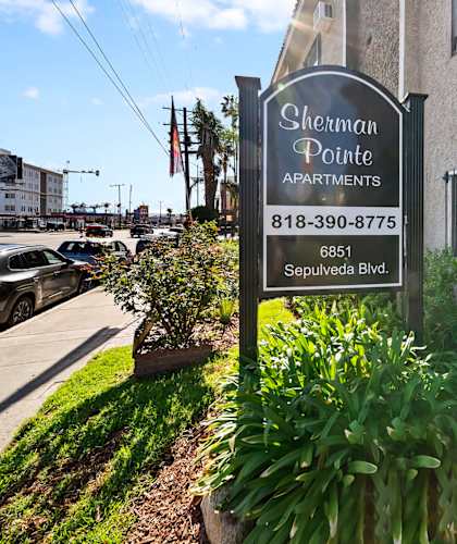 A sign for Sherman Pointe Apartments is in front of a building.