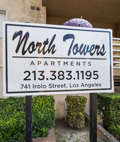 A sign for North Towers Apartments stands in front of a building.