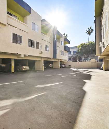 A sunny day at a parking lot with cars and buildings.