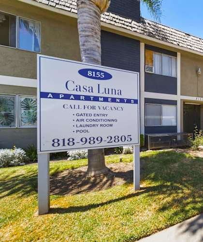 A sign for Casa Luna Apartments is displayed in front of a building.