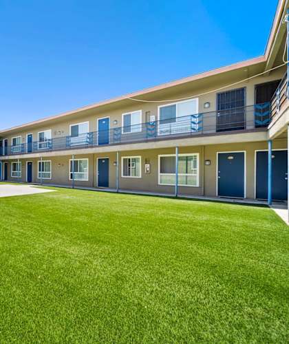A sunny day at the courtyard of a building with blue doors and windows.