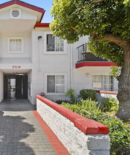 A white building with a red roof and a black awning with the number 5708 on it.