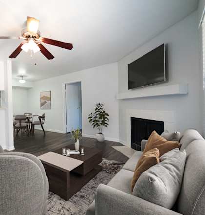 A living room with a grey couch and a ceiling fan.