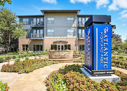 A large building with a sign that says "Atlantis Highland Park Apartment Homes".