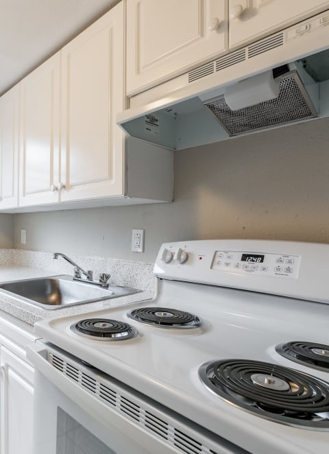  a kitchen with white cabinets and a white stove top oven at Del Rio Apartment
