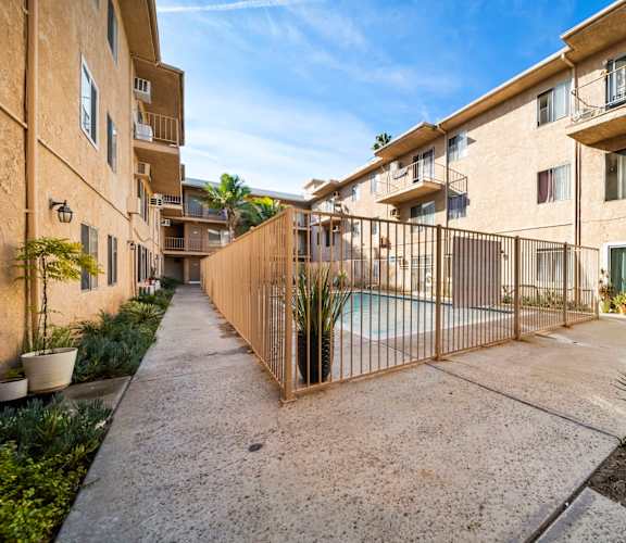 A sunny day at a residential complex with a pool and a fence.