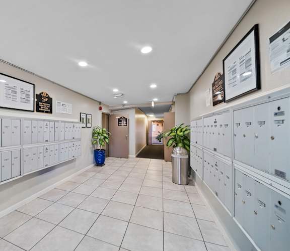 A hallway with white lockers and a blue trash can.