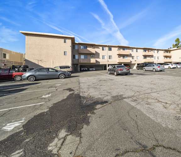A parking lot with a building in the background and several cars parked.