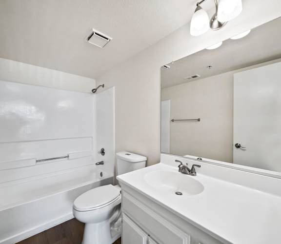 A white bathroom with a toilet, sink, and mirror.