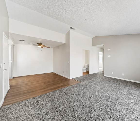 A spacious room with a ceiling fan and carpeted floor.