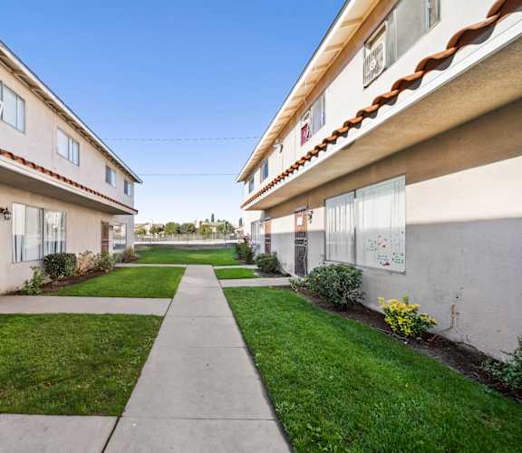 A long concrete walkway separates two rows of houses.