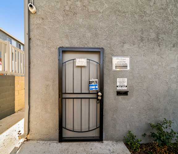A black gate with a blue sign that says "OPEN" in front of a grey wall.