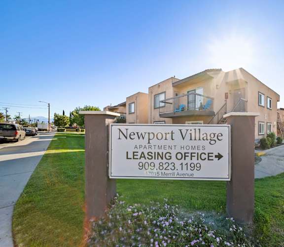 A sign for Newport Village Apartment Homes with a leasing office phone number.