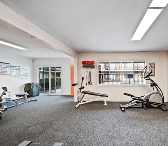 A gym with a variety of equipment including treadmills, weights, and exercise bikes.