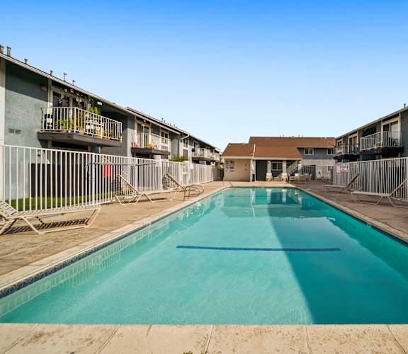 A long rectangular pool in the middle of a courtyard surrounded by buildings.