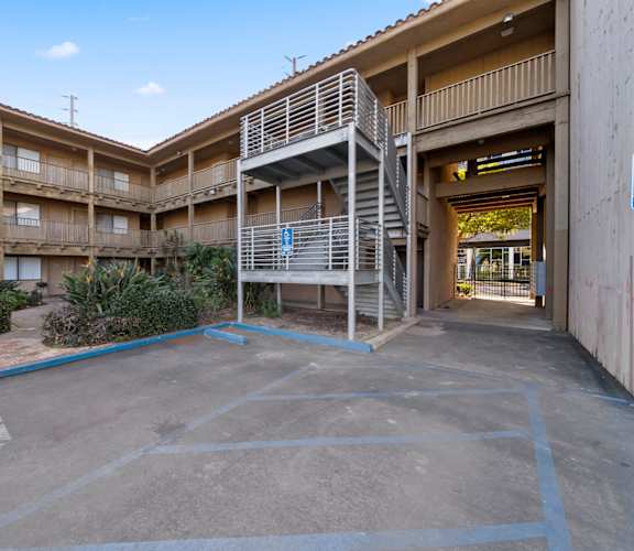 A parking lot with a handicap parking sign and a building in the background.