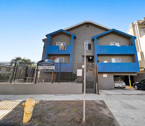 A basketball court is on the side of a two-story apartment building.