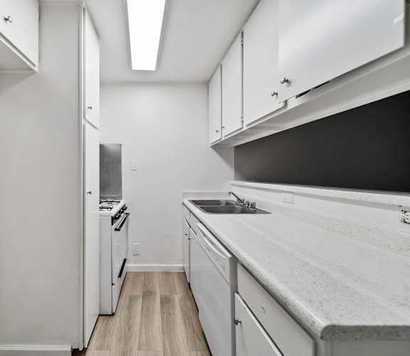 A kitchen with white cabinets and a black counter top.